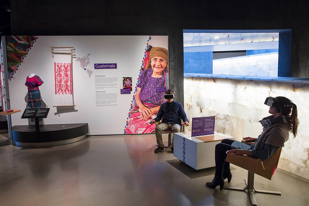 Guatemalan dress on display while 2 people with VR headsets sit in chairs.
